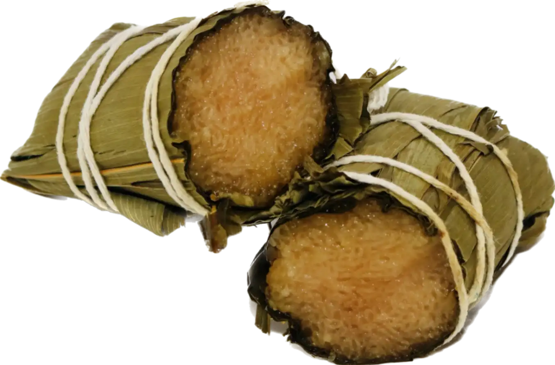 Two zongzi sticky rice dumplings wrapped in bamboo leaves and tied with string, cut open to show the glutinous rice inside