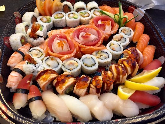 A platter of sushi rolls and nigiri topped with salmon, prawn and fish roe, with lemon slices