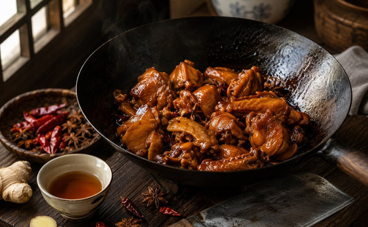 Soy-braised chicken in a wok with a cup of Shaoxing rice wine, ginger and star anise